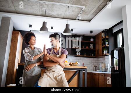 Jeune couple heureux en donnant des tabliers de cuisine de haut en cinq Banque D'Images