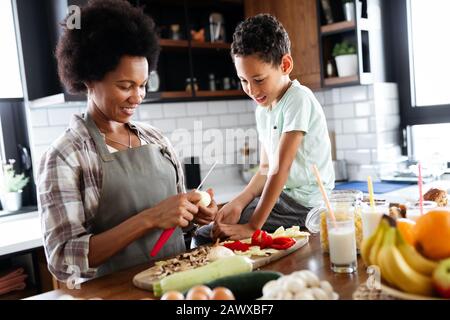 La mère et l'enfant s'amusant de la préparation des aliments dans la cuisine Banque D'Images