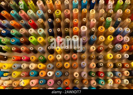 Beaucoup de fils à coudre dans différentes couleurs, fil à coudre trié sur un mur Banque D'Images