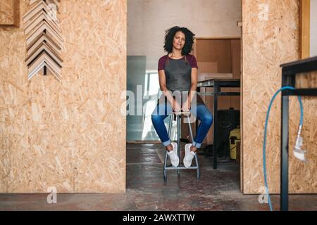 Jeune entrepreneur confiant assis dans son atelier de cadrage Banque D'Images