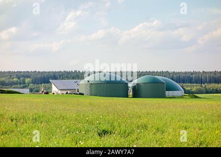 Usine de biogaz, grange avec photovoltaïque, tracteur à part, pré vert en face Banque D'Images