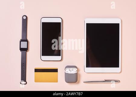 Gadgets modernes, stylo et carte de crédit horizontal de dessus plat composition tourné, fond rose pâle Banque D'Images