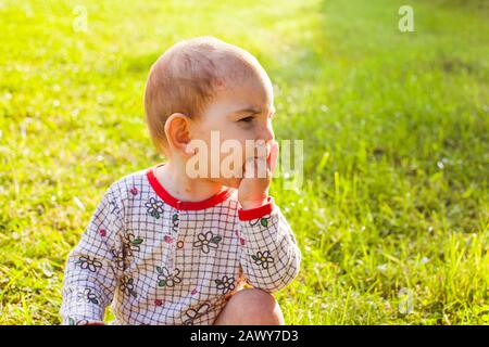 Bébé avec éruption de varicelle assise à l'herbe verte Banque D'Images