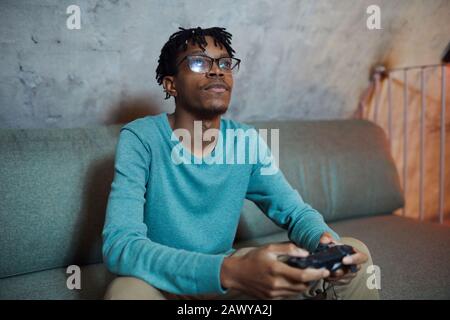 Portrait d'un homme afro-américain souriant jouant aux jeux vidéo via une console de jeu, espace de copie Banque D'Images