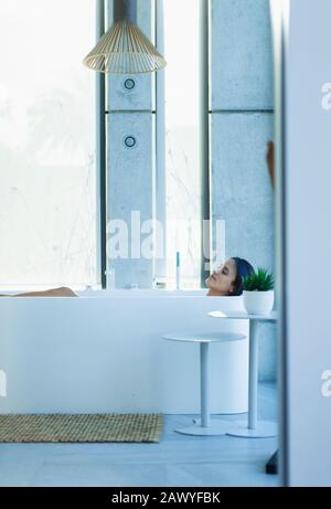 Une femme sereine se détendant dans la baignoire dans la salle de bains moderne Banque D'Images