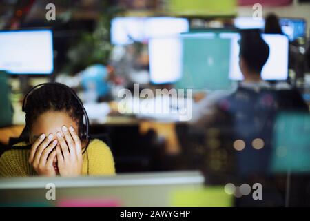 Fatiguée, femme d'affaires stressée avec la tête dans les mains à l'ordinateur au bureau Banque D'Images