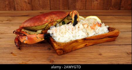 Crabe brun frais entier et viande fraîche dans un plat en bois sur fond de bois avec citron Banque D'Images