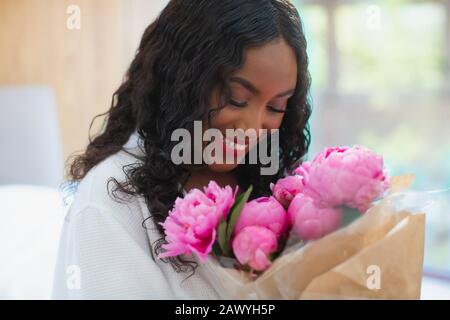 Bonne jeune femme recevant un bouquet de pivoines roses Banque D'Images