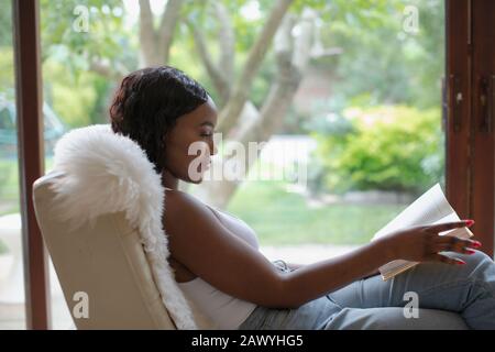 Jeune femme relaxant livre de lecture dans la fenêtre Banque D'Images