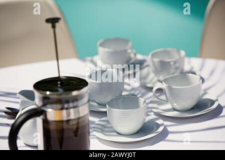 Presse française et tasse à café sur la table de patio ensoleillée Banque D'Images