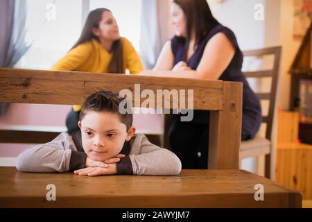 Garçon avec le syndrome De Down jouant sous la table de salle à manger Banque D'Images