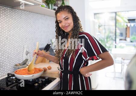 Portrait heureuse jeune femme cuisine sur cuisinière dans la cuisine Banque D'Images
