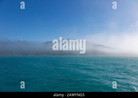 Brouillard se brisant sur les montagnes et l'océan bleu turquoise Groenland Banque D'Images