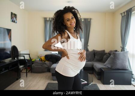 Portrait heureuse jeune femme enceinte dans la salle de séjour Banque D'Images