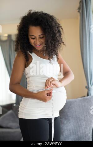 Jeune femme enceinte mesurant l'estomac à l'aide de ruban de mesure Banque D'Images