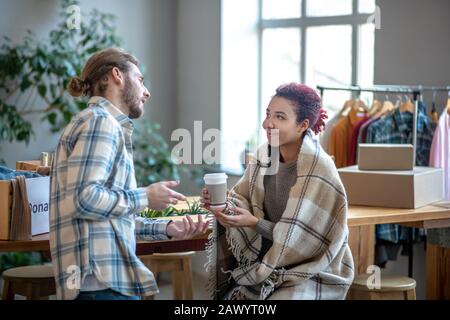 Jeune fille avec un verre de café assis, homme debout. Banque D'Images