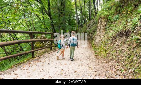 Une fillette blonde avec un sac à dos touristique pointe un doigt sur un lac de montagne. Les enfants en matériel de camping vont en famille un week-end de camping le long d'une gra Banque D'Images