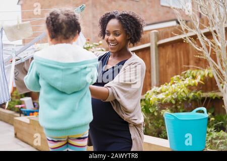 Bonne mère enceinte et fille accrochées à la lessive sur la corde à linge Banque D'Images