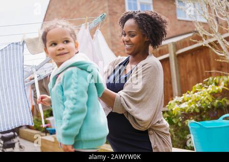 Bonne femme enceinte et fille accrochées à la lessive sur la corde à linge Banque D'Images