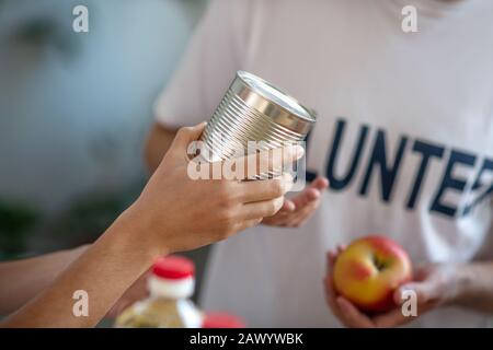 Pot de nourriture en conserve dans les mains d'un volontaire. Banque D'Images