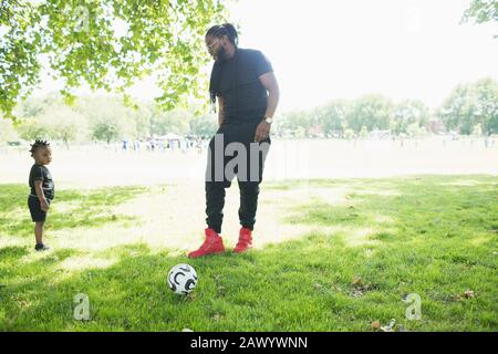 Père et enfant en bas âge jouant au football dans le parc Banque D'Images