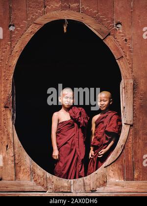 Des moines bouddhistes novices se tenant près de la fenêtre du monastère de Shwe Yan Pyay, dans le village de Nyaung Shwe, près du lac Inle, Myanmar (Birmanie). Banque D'Images
