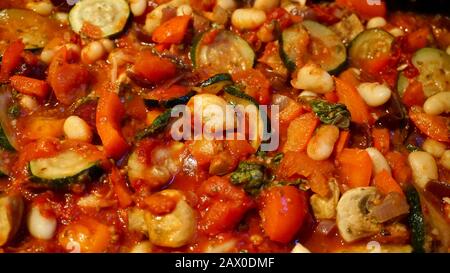 Beany ratatouille, un repas végétalien fait avec des poivrons, des oignons rouges, des courgettes, des champignons, des tomates, des haricots, du basilic, de l'origan et du romarin Banque D'Images