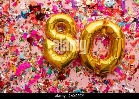 Ballon de fête d'anniversaire numéro 80 sur fond pailleté confetti Banque D'Images