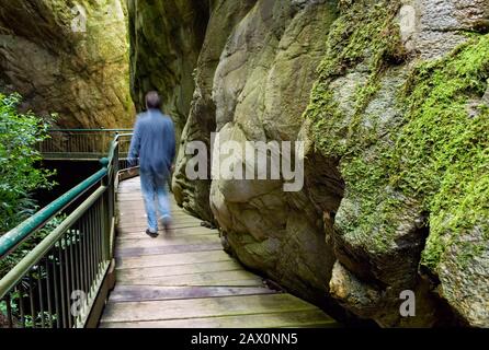 L'homme marchant sur une passerelle traverse les rochers d'un canyon, Orrido di Bellano, Italie Banque D'Images