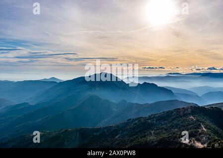 Magnifique paysage captivant de la chaîne de montagnes des Alpes françaises brumeuses en couches dans les Alpes-Maritimes l'après-midi pendant une journée ensoleillée Banque D'Images