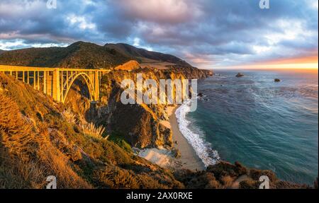 Vue panoramique panoramique sur le pont historique de Bixby Creek le long de la célèbre Highway 1 dans un magnifique coucher de soleil doré au coucher du soleil, Californie, États-Unis Banque D'Images