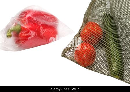 un papier cloche dans un sac en plastique et des tomates et un concombre dans un sac réutilisable en maille verte, comparaison de différents sacs en vrac Banque D'Images