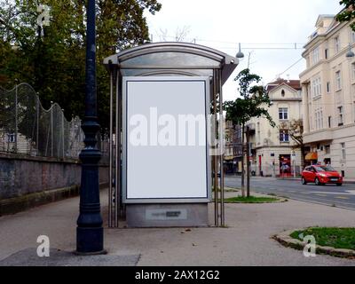 abri de bus de structure de verre. trottoirs et arbres d'automne. panneaux de publicité blancs ad espace. concept de marketing. rue, trafic léger avec voiture rouge Banque D'Images