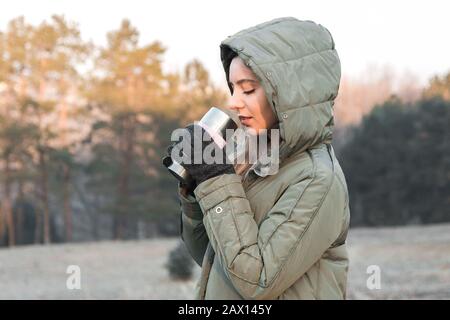 femme touriste en montagne au lever du soleil tenant un thermos avec thé ou café et se réchauffer Banque D'Images