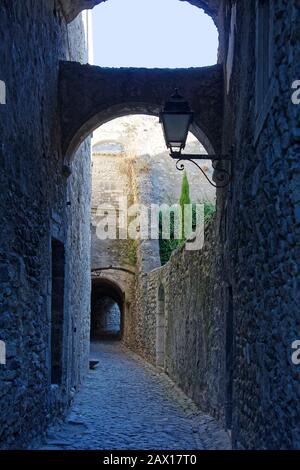 Rue sombre, étroite, piétonne seulement, pavée, vieille, arches, sombre, solitaire, peu accueillant, soleil, ombre, Viviers, France; été, vertical Banque D'Images