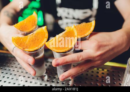 Bartender pouring strong boisson alcoolisée dans de petits verres sur bar, shots Banque D'Images