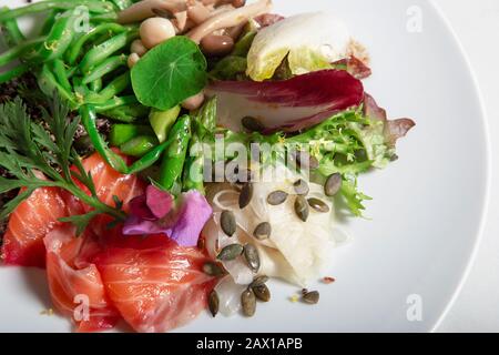 Gros plan du plat de saumon mariné dans la betterave et l'aneth. Haricots verts de Perona, fenouil mariné, asperges vertes, champignons marinés et graines de citrouille. Iso Banque D'Images