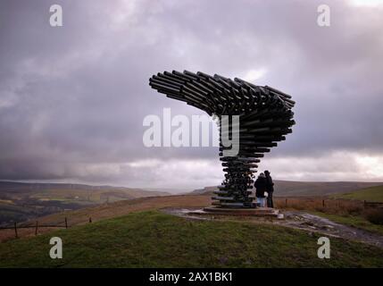 Deux figures se tenant sous l'arbre De chant sur un jour nuageux dans une lumière dramatique. Banque D'Images