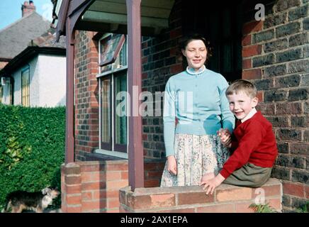 Garçon de six ans avec sa mère à l'extérieur d'un bungalow en 1960 Banque D'Images