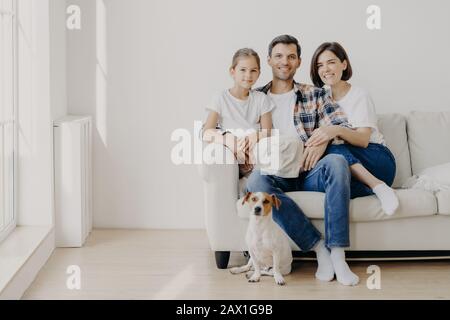 Vue horizontale de trois membres de la famille sympathiques et de petits chiens pedigree pose à l'appareil photo pour faire des photos inoubliables. Dauther passe du temps libre avec Banque D'Images