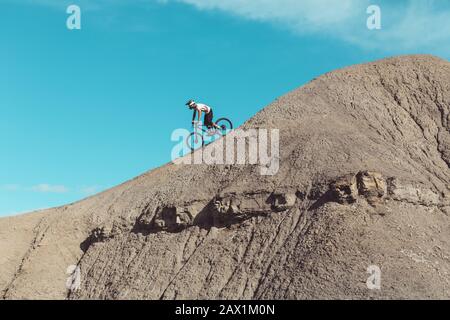 Vue latérale du Mountainbiker sur un terrain escarpé dans le désert Banque D'Images