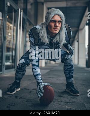 Homme vêtu comme joueur d'équipe de football américain avec ballon dans sa main. Banque D'Images