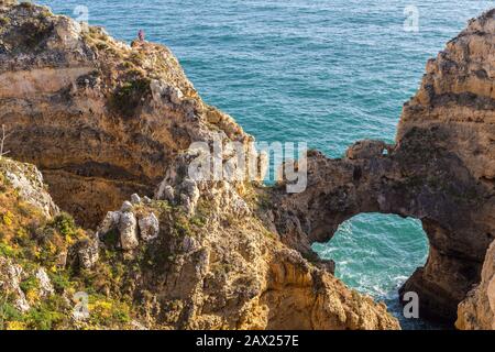 Personne debout sur des falaises près de l'arche naturelle, Pont Piedade, Algarve, Porgugal Banque D'Images