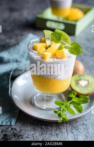 Pudding de graines de cococotier végétalien avec purée de mangue et surmontée de tranches de kiwi dans un bocal en verre Banque D'Images
