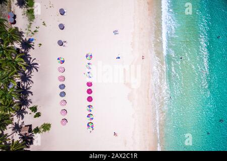 Vue sur la plage avec parasols colorés et bains de personnes au soleil sur la plage de Nacpan à El Nido, Palawan, Philippines.