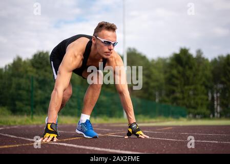 Homme musclé dans un t-shirt et un short. Courir dans le stade. Banque D'Images