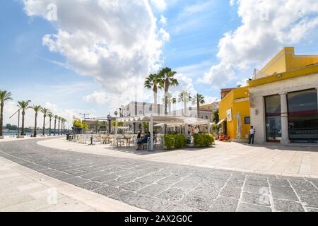 Les touristes peuvent profiter d'une journée d'été ensoleillée sur la promenade en bord de mer à la ville portuaire de Brindisi Italie dans la région des Pouilles Banque D'Images