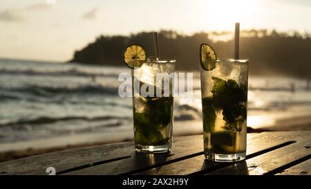 Des boissons fraîches de mojito, deux verres contre le coucher du soleil pendant une soirée chaude sur la plage Banque D'Images