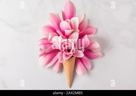 Cône de crème glacée avec des fleurs de Magnolia rose printemps composition sur fond blanc. Concept de ressort minimal. Plat. Vue de dessus Banque D'Images