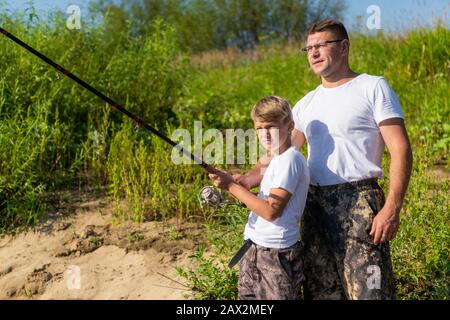 Père et fils étirant une tige de pêche avec du poisson sur le crochet Banque D'Images